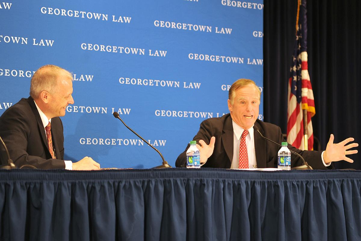 Two men speaking at a panel.