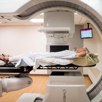 A women laying down on a proton therapy machine.